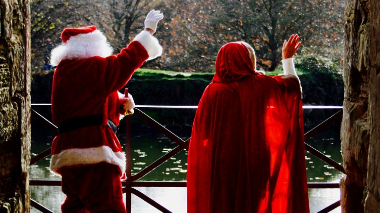 Father and Mother Christmas waving across the moat at Bodiam Castle, East Sussex